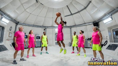 Jumping mid-air inside a white dome, an athlete shoots a basketball as teammates watch