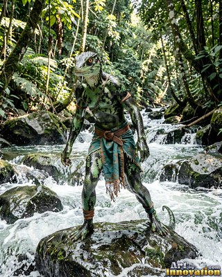 Standing on a wet rock, a green lizard person balances above a rushing forest stream