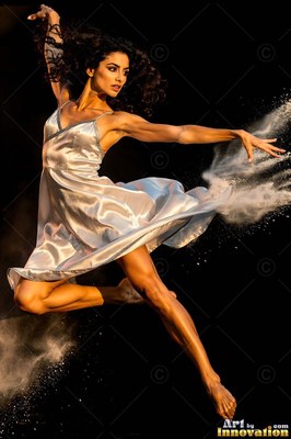 Woman in a white dress leaping through white powder on black