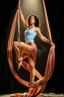 A woman hangs from peach silk ribbons, illuminated by a warm top spotlight