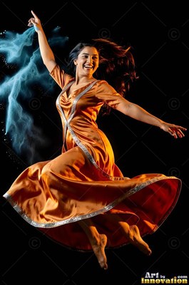 Leaping in midair against black, a smiling woman wears an orange dress