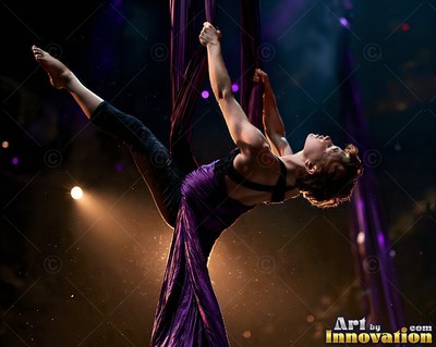 On a dark stage, a woman in purple fabric leans back from aerial silks