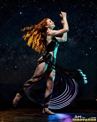 A red-haired woman dances in a black dress under starry blue night light