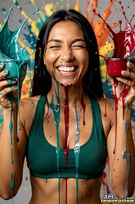 A laughing woman in a green top holds small pots of splashing teal and red paint