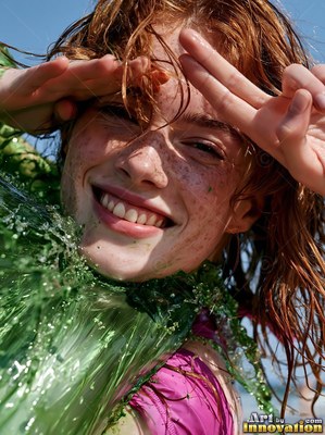 Smiling redheaded woman splashed with green paint