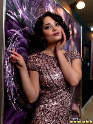 A woman in a sparkly pink dress leans against a purple painted backdrop