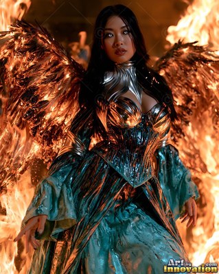 Silver breastplate worn by a winged woman standing before a wall of orange flames