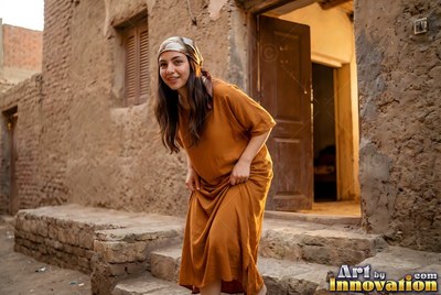 A woman in a rust linen dress on the worn stone steps of a mudbrick house in Giza, warm light spilling from the open doorway behind her