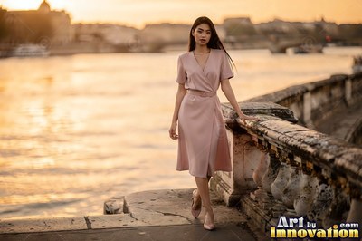 Walking along a stone quay by the river, a woman in a pink dress at sunset