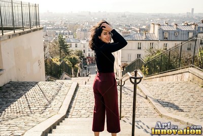 A woman pauses on cobblestone steps above Paris in bright afternoon sun