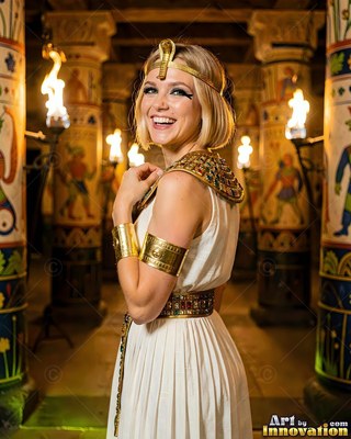 A woman in an Egyptian costume smiles by torchlight in a temple hallway