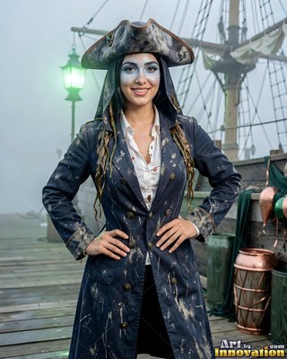 Standing with hands on hips on a foggy ship deck, a woman is dressed in a pirate coat