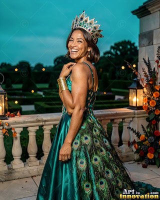 A grinning woman turns in a peacock feather dress under the dim teal evening sky