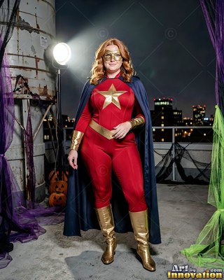Standing on a night rooftop, a woman models a red superhero suit with a cape