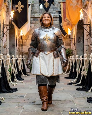 Walking forward in a stone courtyard, a smiling woman models steel plate armor