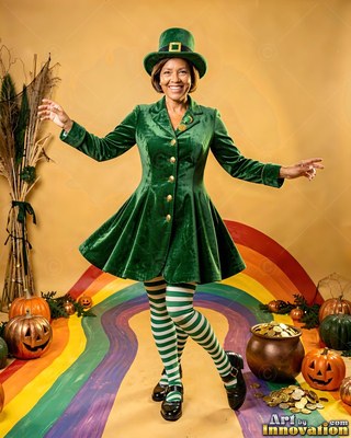 A smiling woman dances in a green leprechaun coat over a painted rainbow floor