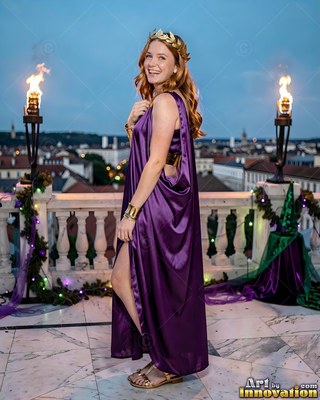 Woman in a purple toga smiling on a balcony by torches