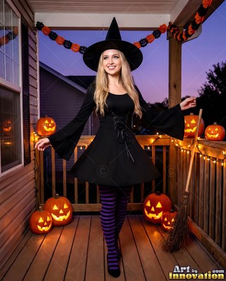 Pointed witch hat on a woman smiling posing on a porch lit by jack-o'-lanterns
