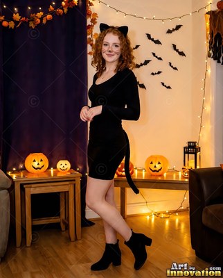 Turned sideways in a decorated room, a woman has on a black cat costume