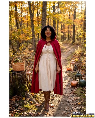 Standing on an autumn trail, a grinning woman stands in a long red hooded cape