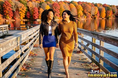 Two smiling women walk along a wooden dock by an autumn lake