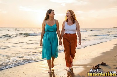 In a teal sundress, a woman holds hands with her friend walking barefoot on a beach at sunset