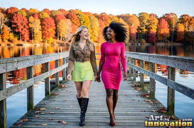 Two women smiling and walking along a wooden dock by fall trees