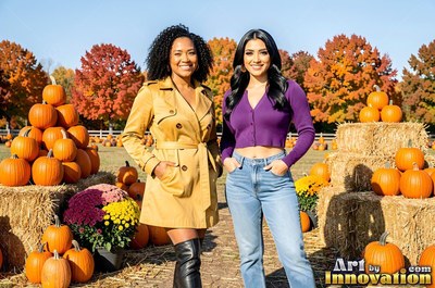 Two cheerful women stand beside hay bales in a pumpkin patch under bright autumn sun