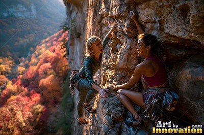 Two women rock climb a steep cliff in warm sunlight