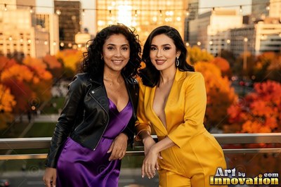 Leaning side by side on a balcony, two grinning women pose above autumn trees