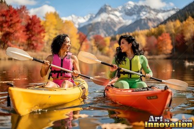 On a calm mountain lake, two smiling women paddle colorful kayaks in autumn sunlight