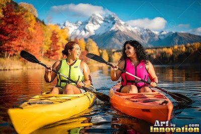 Two adult women kayak on a clear lake under bright sunlight before snowy peaks