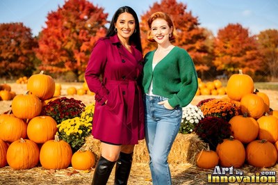 In a sunny pumpkin patch, two smiling women pose together outdoors