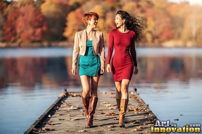 Two women walk on a wooden dock by an autumn lake