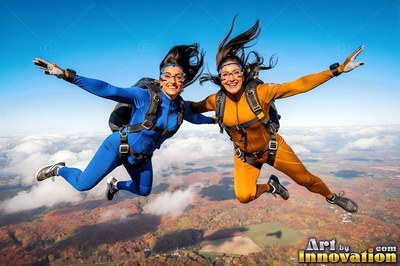 Two women skydive side by side over autumn hills in bright blue and orange jumpsuits