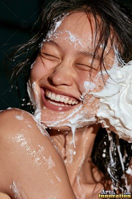 A laughing woman gets hit in the face with white cream