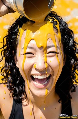 A grinning woman finds herself yellow paint poured over her dark curls in bright sunlight