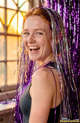Woman with a smile covered in shiny purple and silver tinsel streamers