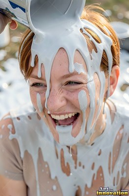 Woman chuckles as thick gray paint pours over her head