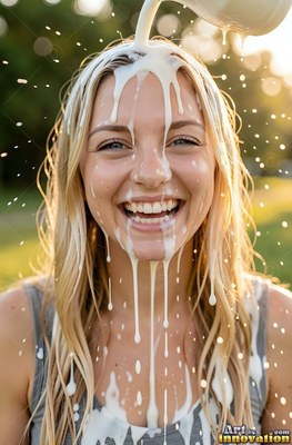 A smiling blonde-haired woman gets milk poured over her head in warm evening sunlight