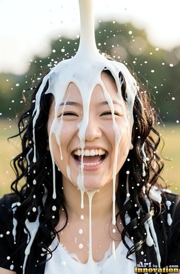 In a sunny park, a laughing woman gets white milk poured over her head