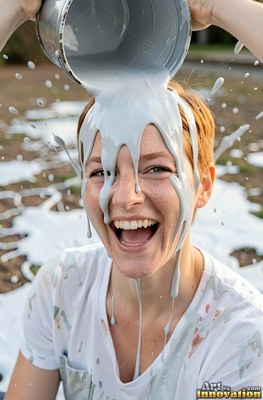 A woman giggles as thick gray paint is poured over her head
