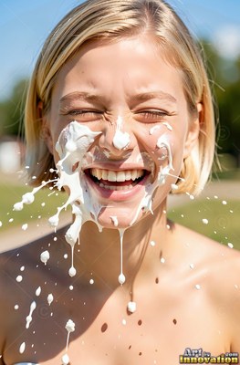 A smiling blonde woman laughs outside with thick white cream splattered on her face