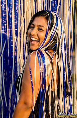Smiling woman covered in blue and white party streamers in warm sunlight