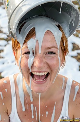 Laughing openly, a freckled woman has thick white paint poured over her head from a bucket
