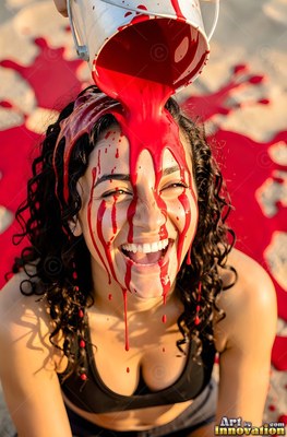 Woman giggles as red paint pours over her head outdoors