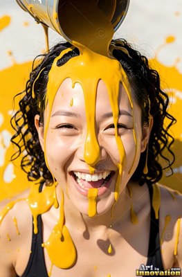 Laughing outdoors, a woman is thick yellow paint poured onto her face and hair
