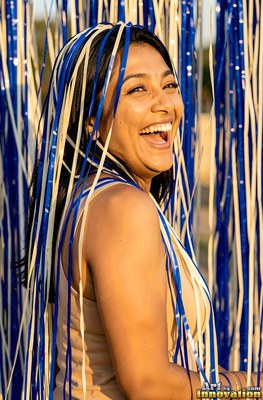 Turned over her shoulder outdoors, a woman chuckles under blue streamers
