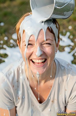 Outdoors in a grassy yard, a grinning woman is thick gray paint poured on her head
