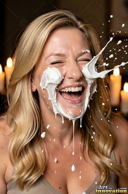 A woman with blonde hair laughing as cream splashes on her face